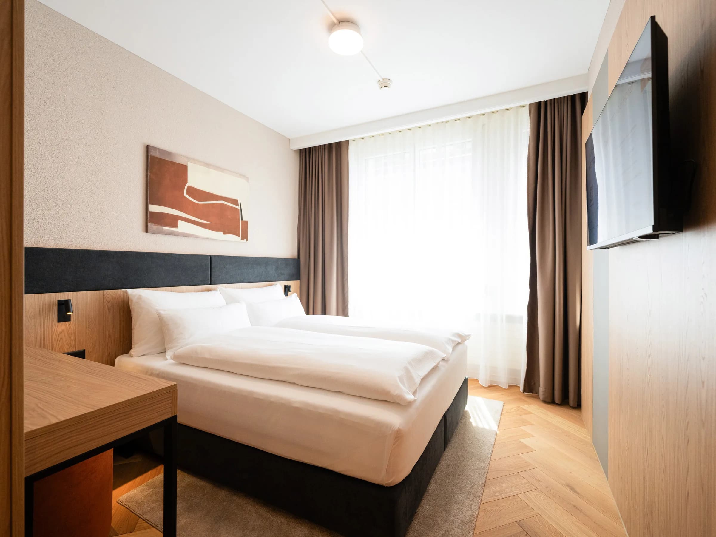 Zimmer im Hotel Metropol in St. Gallen mit Doppelbett, dunklem Kopfteil und Fensterfront