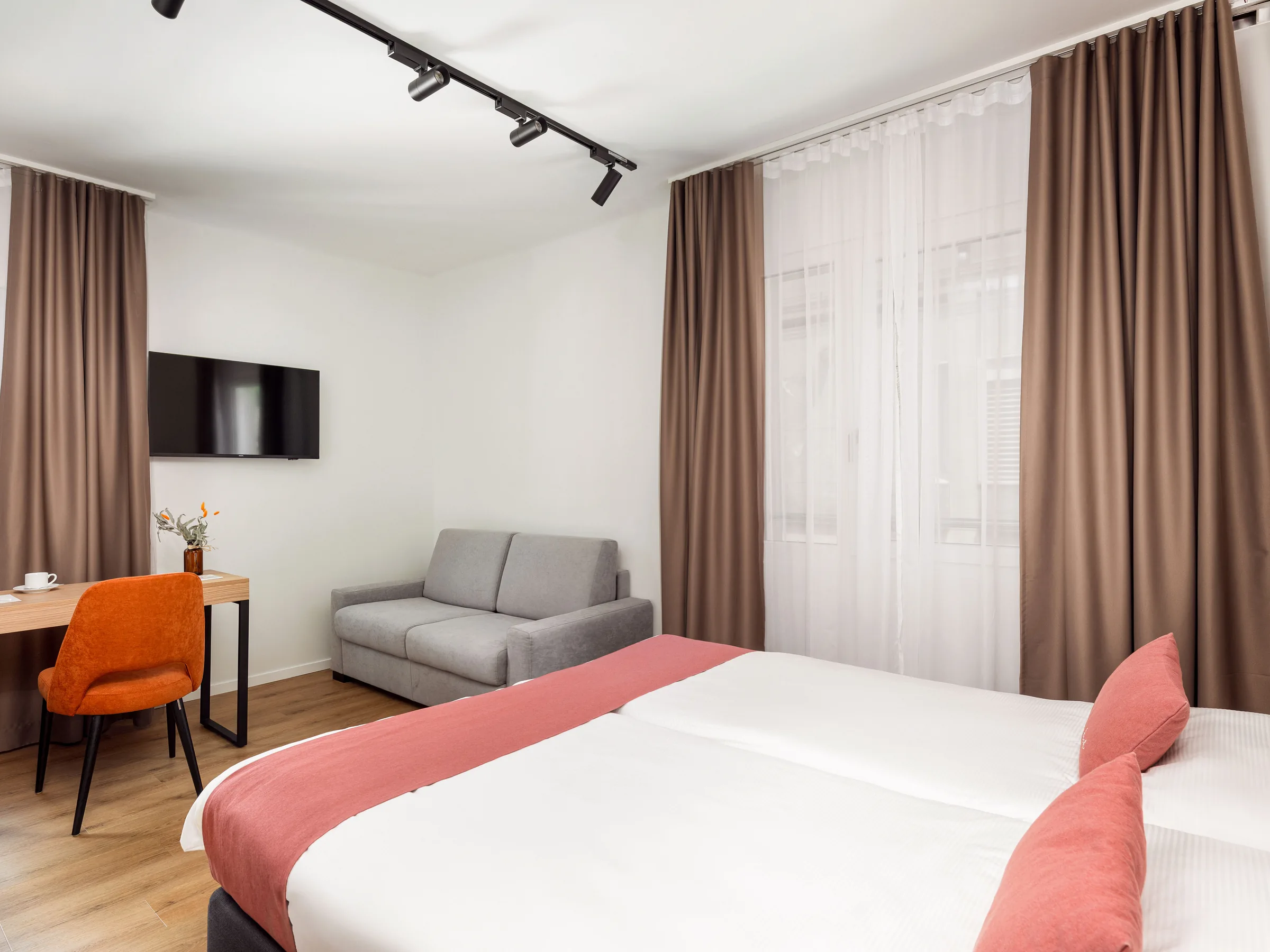 Doppelzimmer im Hotel Al Giardinetto in Biasca mit Schreibtisch, Sofa und bodenlangen Vorhängen